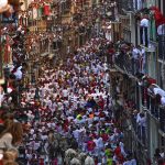 
              FILE - People run through the streets with fighting bulls and steers during the first day of the running of the bulls at the San Fermin festival in Pamplona, northern Spain, Thursday, July 7, 2022. From the start _ July 6 _ the tension and excitement was palpable as tens of thousands of people donning the customary white trousers and shirt with red sash and neckerchief packed the town hall square for the traditional "chupinazo" firework that kicks off the nine-day festival. (AP Photo/Alvaro Barrientos, File)
            