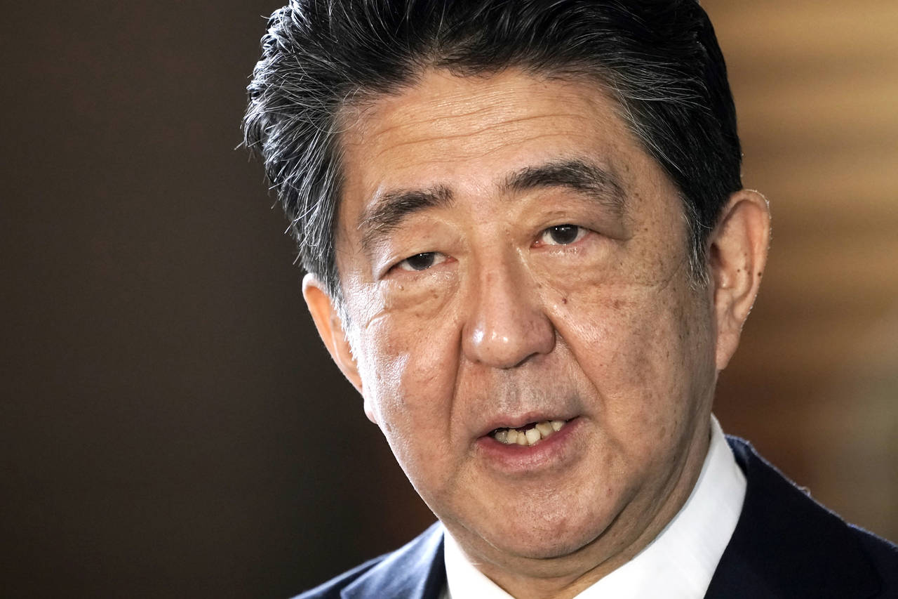 FILE - Japan's outgoing Prime Minister Shinzo Abe speaks to the media as he arrives at the prime mi...