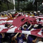 
              FILE - South Korean students tear a huge Japanese rising sun flag during a rally denouncing Japanese Prime Minister Shinzo Abe's statement to mark the 70th anniversary of the end of World War II, near the Japanese Embassy in Seoul, South Korea on Aug. 15, 2015. Japan’s longest-serving prime minister, Shinzo Abe was credited with instilling political and economic stability. However, he angered Japan’s neighbors South Korea and China along with many Japanese with his nationalistic rhetoric and calls to revise the country’s pacifist constitution. (AP Photo/Lee Jin-man, File)
            