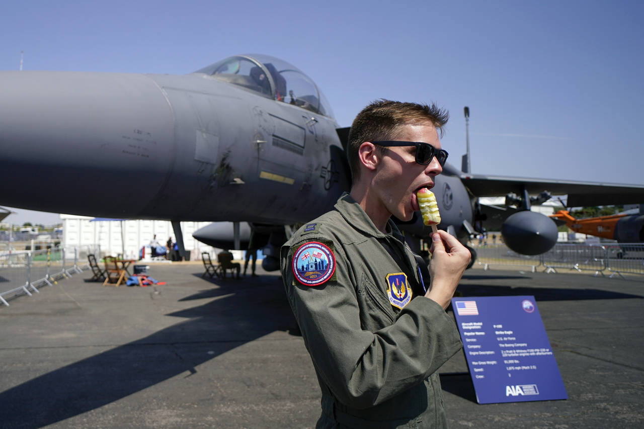 FILE - A member of the military personnel eats an ice cream as he stands past an F15E Strike Eagle ...