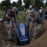 
              Soldiers lay the coffin of 40-year-old Volodymyr Miroshnychenko who was killed on the frontlines of Marinka, during his funeral procession at a cemetery in Pokrovsk, eastern Ukraine, Friday, July 15, 2022. (AP Photo/Nariman El-Mofty)
            