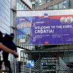 
              A journalist films a banner welcoming Croatia to the euro in front of EU headquarters in Brussels, Tuesday, July 12, 2022. The European Union is set on Tuesday to remove the final obstacles for Croatia to adopt the euro, ensuring the first expansion of the currency bloc in almost a decade. (AP Photo/Virginia Mayo)
            