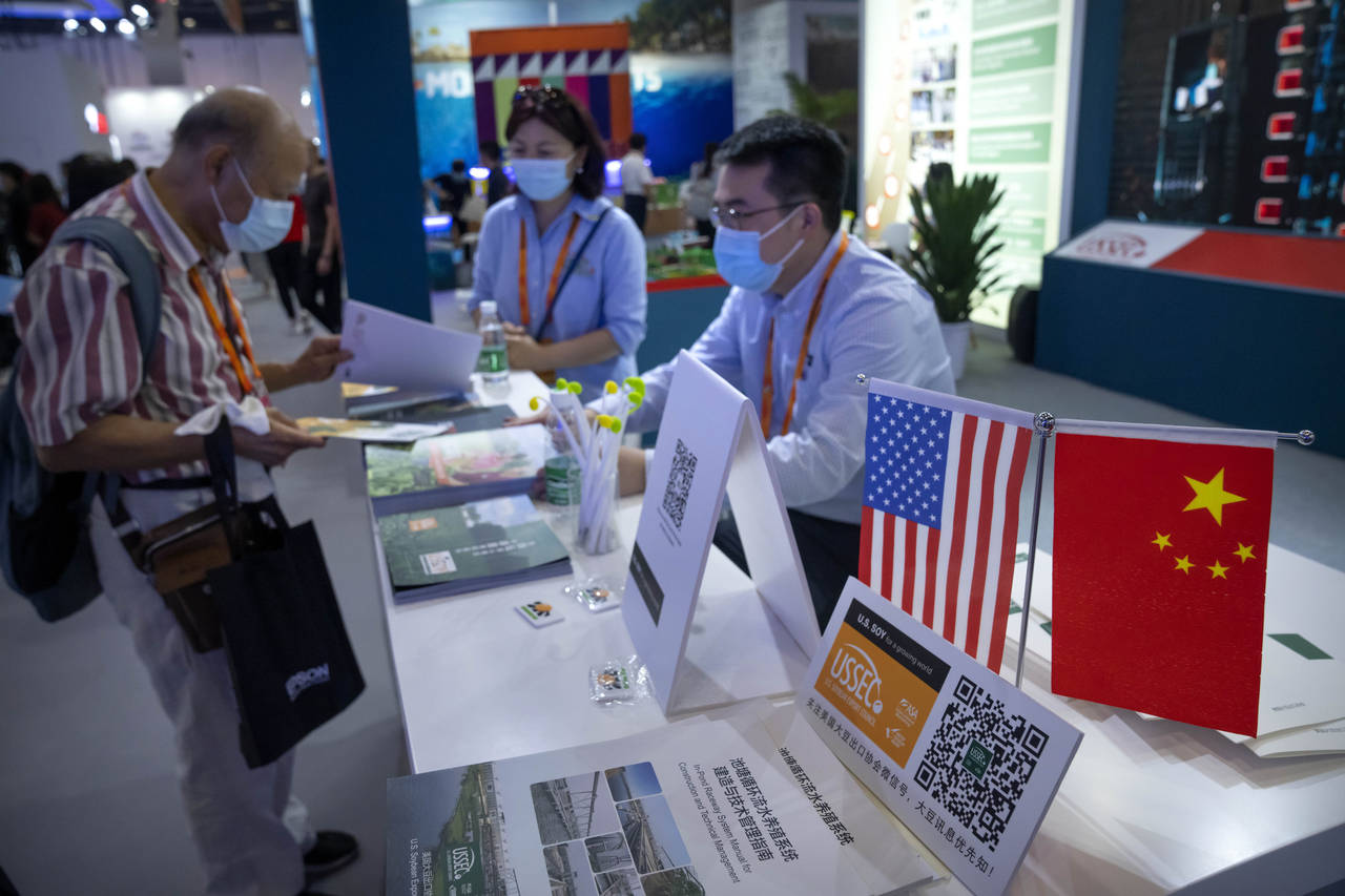 Staff members stand near American and Chinese flags at a booth for the U.S. Soybean Export Council ...