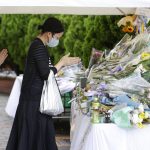 
              People pray at a memorial area set up near the scene of former Japanese Prime Minister Shinzo Abe's assassination in Nara, western Japan, Wednesday, July 13, 2022. Abe was assassinated on July 8 during his election campaign speech. Japanese police said Wednesday they have found a number of what they believe are bullet marks on a building near the site of Abe's assassination last week in western Japan, apparently from the first shot fired from a suspect's powerful homemade gun that narrowly missed Abe. (Yosuke Mizuno/Kyodo News via AP)
            