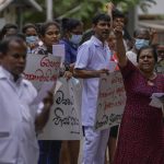 
              Government hospital staff members shout anti-government slogans condemning the eviction of protesters from the president's office using military force in Colombo, Sri Lanka, Saturday, July 23, 2022. (AP Photo/Eranga Jayawardena)
            