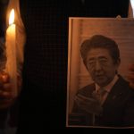 
              An Indian man holds a candle and photo of Japan's former Prime Minister Shinzo Abe during a prayer meeting to pay their respects at Japan Information and Study Centre in Ahmedabad, India, Saturday, July 9, 2022. Abe was shot in the Japan's western city of Nara on Friday and airlifted to a hospital but died of blood loss. (AP Photo/Ajit Solanki)
            