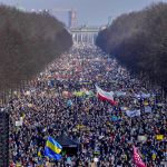 
              FILE - People walk down the bulevard 'Strasse des 17. Juni' ahead of a rally against Russia's invasion of Ukraine in Berlin, Germany, on Feb. 27, 2022. By ending 77 years of almost uninterrupted peace in Europe, war in Ukraine war has joined the dawn of the nuclear age and the birth of manned spaceflight as a watershed in history. After nearly a half-year of fighting, tens of thousands of dead and wounded on both sides, massive disruptions to supplies of energy, food and financial stability, the world is no longer as it was. (AP Photo/Markus Schreiber)
            