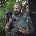 
              A Ukrainian soldier smiles as he looks at his puppy, in the Donetsk region, Ukraine, Saturday, July 2, 2022. (AP Photo/Efrem Lukatsky)
            