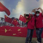 
              A couple pose in front of a banner featuring Chinese flags at an exhibition to mark the 25th anniversary of the former British colony's return to Chinese rule, in Hong Kong, Friday, June 24, 2022. Many in Hong Kong worry that communist-ruled China is exerting ever more control over semi-autonomous Hong Kong. Critics of Beijing's policies say it is contrary to its promises to respect Hong Kong’s civil liberties and its semi-autonomous status for 50 years. (AP Photo/Kin Cheung)
            