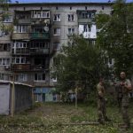 
              Ukrainian soldiers stand in front of a five-story residential building damaged from a rocket attack on a residential area, in Kramatorsk, eastern Ukraine, Tuesday, July 19, 2022. (AP Photo/Nariman El-Mofty)
            