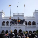 
              Sri Lankan protesters, some carrying national flags, stand on top of prime minister Ranil Wickremesinghe 's office, demanding he resign after president Gotabaya Rajapaksa fled the country amid economic crisis in Colombo, Sri Lanka, Wednesday, July 13, 2022. Sri Lanka’s president fled the country without stepping down Wednesday, plunging a country already reeling from economic chaos into more political turmoil. Protesters demanding a change in leadership then trained their ire on the prime minister and stormed his office. (AP Photo/Eranga Jayawardena)
            