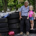 
              Larry Guess, 72, and his granddaughter Avery Moore, 4, sit outside on some old tires on Thursday, June 23, 2022, in Athens, Ala. His son, David Guess, a 51-year-old small-town father of four, was shot by an acquaintance in March after an argument over a car part. (AP Photo/Brynn Anderson)
            