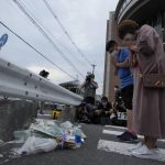 
              People pray after putting a bouquet of flowers at a makeshift memorial at the scene where the former Prime Minister Shinzo Abe was shot while delivering his speech to support the Liberal Democratic Party's candidate during an election campaign in Nara, Friday, July 8, 2022.  Former Japanese Prime Minister Shinzo Abe, a divisive arch-conservative and one of his nation's most powerful and influential figures, has died after being shot during a campaign speech Friday in western Japan, hospital officials said.(AP Photo/Hiro Komae)
            