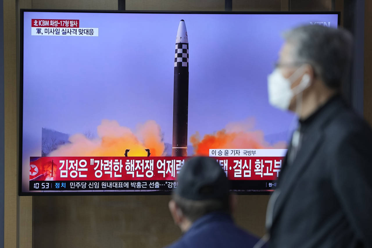 FILE - People watch a television screen showing a news program reporting about North Korea's interc...