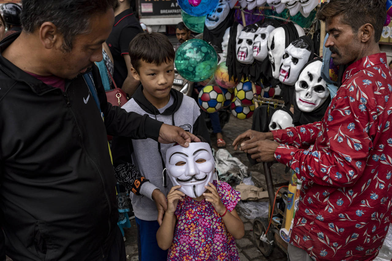 A child tries on a mask at a street vendor in Dharmsala, India, Saturday, June 18, 2022. Summer tra...
