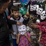 
              A child tries on a mask at a street vendor in Dharmsala, India, Saturday, June 18, 2022. Summer travel is underway across the globe, but a full recovery from two years of coronavirus could last as long as the pandemic itself. (AP Photo/Ashwini Bhatia)
            