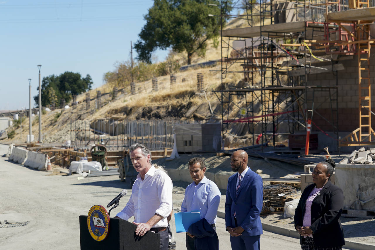Governor Gavin Newsom, center, talks to reporters during a press conference at the construction sit...