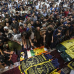 
              Mourners pray next to the bodies of Khaled Mansour a senior commander in the Palestinian militant group Islamic Jihad and other Palestinians who were killed in Israeli airstrikes, during their funeral in Rafah, southern Gaza Strip, Sunday, Aug. 7, 2022. Israel has killed two senior Islamic Jihad militants in three days of air strikes in the Gaza Strip, and Palestinian militants have launched nearly 600 rockets at Israel. Palestinian officials say at least 31 people in Gaza have died. (AP Photo/Yousef Masoud)
            