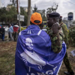 
              A police officer gestures to a supporter of presidential candidate Raila Odinga, seen on his shawl, outside the Supreme Court in Nairobi, Kenya Monday, Aug. 22, 2022. Odinga filed a Supreme Court challenge to last week's election result, asserting that the process was marked by criminal subversion and seeking that the outcome be nullified and a new vote be ordered. (AP Photo/Ben Curtis)
            