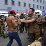 
              A police officer pushes back an anti-government protester during a protest march in Colombo, Sri Lanka, Thursday, Aug. 18, 2022. (AP Photo/Eranga Jayawardena)
            