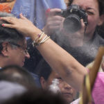 
              An Indigenous woman spits water onto the head of President-elect Gustavo Petro, during a 'popular and spiritual' inauguration ceremony presided over by local Indigenous groups and feminist activists, in Bogota, Colombia, Saturday, Aug. 6, 2022. Petro, the first left-wing Colombian president in 200 years, will be sworn in as the country’s new president on Sunday, Aug. 7.  (AP Photo/Ariana Cubillos)
            