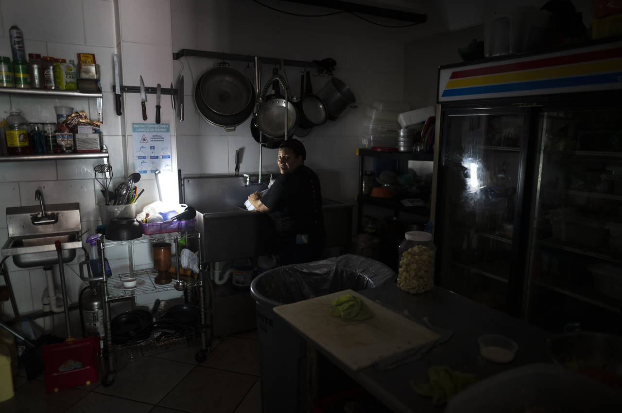 FILE - Las Palmas Cafe employees work with power from a generator during an island-wide blackout in...