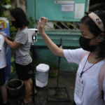 
              CORRECTS LOCATION A student checks her temperature during the opening of classes at the San Juan Elementary School in metro Manila, Philippines on Monday, Aug. 22, 2022. Millions of students wearing face masks streamed back to grade and high schools across the Philippines Monday in their first in-person classes after two years of coronavirus lockdowns that are feared to have worsened one of the world's most alarming illiteracy rates among children. (AP Photo/Aaron Favila)
            
