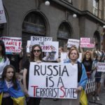 
              Relatives of soldiers from the Azov Regiment and protesters hold banners against Russia in Lviv, Ukraine, on Thursday, Aug, 18, 2022. A small group of anti-Russian protesters gathered on a street corner along a route where visiting leaders will travel to meet Ukrainian President Volodymyr Zelenskyy. The Ukrainian leader is due to meet United Nations Secretary General Antonio Guterres and Turkish President Recep Tayyip Erdogan in the city which is near Ukraine's border with Poland. (AP Photo/Evgeniy Maloletka)
            