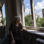 
              Ida Svystunova, 89, looks out the damaged room adjoining her apartment from a May rocket attack in Sloviansk, Donetsk region, eastern Ukraine, Sunday, Aug. 7, 2022. Svystunova is one of only four people left living in the block and spends most of her day looking out the window. "I sit and wait for the end of this war or maybe the end of ourselves," she said. (AP Photo/David Goldman)
            