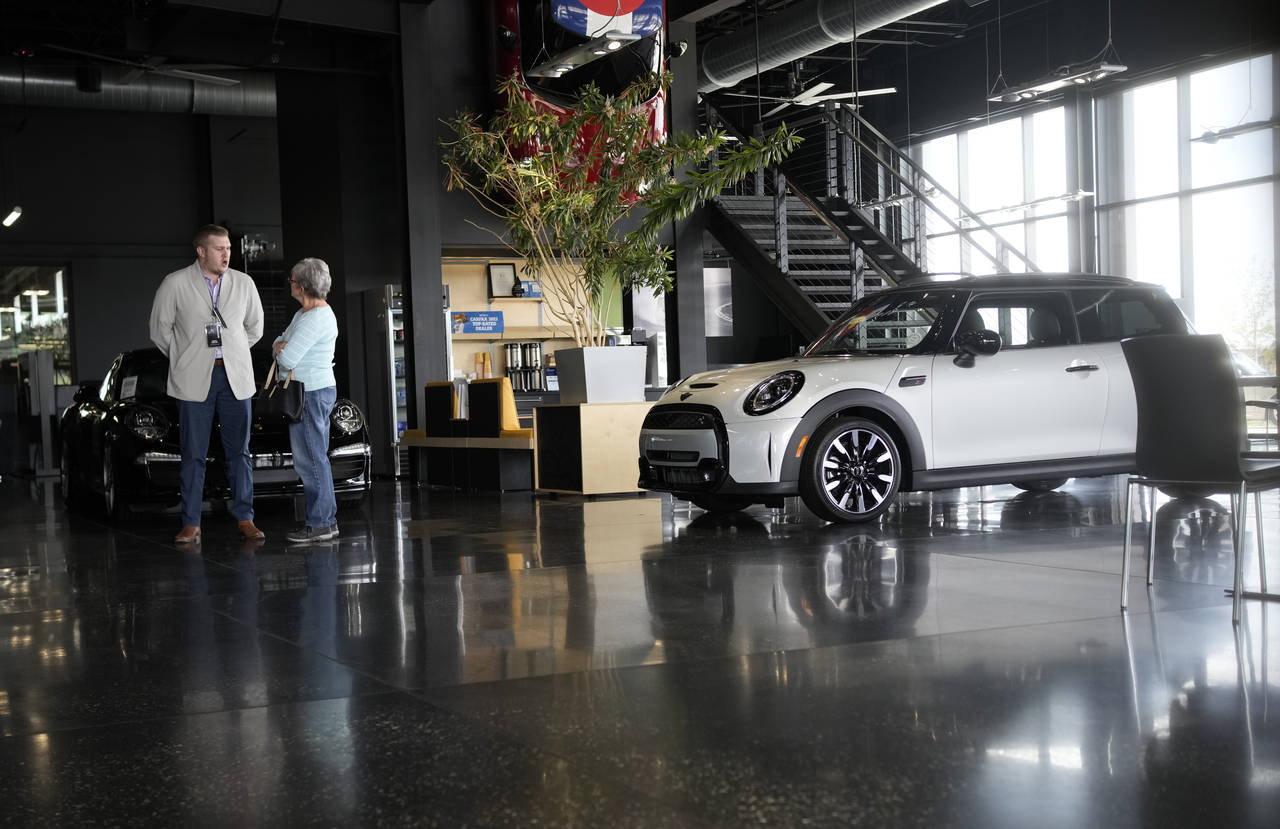 FILE - Prospective buyer chats with a sales associate as a 2022 Cooper S hardtop sits on the otherw...