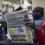 
              A man reads a newspaper to follow the election vote-tallying in Nairobi, Kenya, Friday, Aug. 12, 2022. Vote-tallying in Kenya's close presidential election isn't moving fast enough, the electoral commission chair said Friday, while parallel counting by local media dramatically slowed amid concerns about censorship or meddling. (AP Photo/Mosa'ab Elshamy)
            