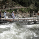 
              People cross a river on a bridge damaged by floodwaters, in the town of Bahrain, Pakistan, Tuesday, Aug. 30, 2022. The United Nations and Pakistan issued an appeal Tuesday for $160 million in emergency funding to help millions affected by record-breaking floods that have killed more than 1,150 people since mid-June. (AP Photo/Naveed Ali)
            