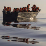 
              Migrants with life jackets provided by volunteers of the Ocean Viking, a migrant search and rescue ship run by NGOs SOS Mediterranee and the International Federation of Red Cross (IFCR), still sail in a wooden boat as they are being rescued  Saturday, Aug. 27, 2022, some 26 nautical miles south of the Italian Lampedusa island in the Mediterranean sea. 87 survivors, including 3 women, 25 minors were rescued in the rescue operation. (AP Photo/Jeremias Gonzalez)
            