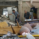 
              Viktor Bielkin, left, and Anatolii Slobodianik, sift through the rubble of the Kramatorsk College of Technologies and Design, where they're maintenance workers, after it was hit in an early morning rocket attack in Kramatorsk, Donetsk region, eastern Ukraine, Friday, Aug. 19, 2022. Russia continued to shell towns and villages in Ukraine's embattled eastern Donetsk region, according to regional authorities, where Russian forces are pushing to overtake areas still held by Ukraine. (AP Photo/David Goldman)
            