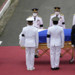 
              Widow and former first lady Amelita Ramos, left, with military chief Lieutenant General Bartolome Vicente Bacarro, second from left, stands beside the flag-draped casket of her husband, the late former Philippine President Fidel V. Ramos, during his state funeral at the Heroes' Cemetery in Taguig, Philippines on Tuesday Aug. 9, 2022. Ramos was laid to rest in a state funeral Tuesday, hailed as an ex-general, who backed then helped oust a dictatorship and became a defender of democracy and can-do reformist in his poverty-wracked Asian country. Ramos died at age 94. (AP Photo/Aaron Favila)
            