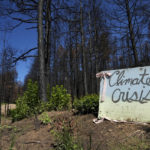 
              A sign reading "climate crisis" sits on a resident's burned property Tuesday, Aug. 9, 2022, in Gallinas, N.M. Earlier this year the area already endured the devastation of the state's largest fire in recorded history, caused by federal officials carrying out what was supposed to be a prescribed burn to lessen the wildfire danger. Now, those same charred lands under deluge from a powerful seasonal monsoon are channeling contaminated runoff into the city's drinking water supply. (AP Photo/Brittany Peterson)
            