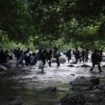 
              FILE - Migrants cross the Acandi River in Acandi, Colombia, Sept. 15, 2021, as they continue on their trek north towards the jungle known as the Darien Gap. Venezuelan migrants have started joining others traveling over land through the dense, lawless jungle on the Colombia-Panama border, after they became unable to fly to Mexico as tourists in Jan. 2022. (AP Photo/Fernando Vergara, File)
            