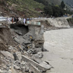 
              Passengers wait by a damaged road next to floodwaters, in Bahrain, Pakistan, Tuesday, Aug. 30, 2022. Disaster officials say nearly a half million people in Pakistan are crowded into camps after losing their homes in widespread flooding caused by unprecedented monsoon rains in recent weeks. (AP Photo/Naveed Ali)
            