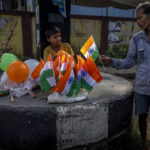 
              A rickshaw puller buys an Indian flag from a boy near a traffic intersection on Independence Day in Gauhati, northeastern state of Assam, India, Monday, Aug. 15, 2022. The country is marking the 75th anniversary of its independence from British rule. (AP Photo/Anupam Nath)
            