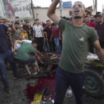 
              A youth reacts while other residents inspect a wounded horse near a damaged car that was hit in an Israeli airstrike that killed people in the car and the horse cart, at the main road in Gaza City, Sunday, Aug. 7, 2022. (AP Photo/Adel Hana)
            