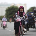 
              A girl rides her bicycle to school in Phnom Penh, Cambodia, Tuesday, Aug. 2, 2022. (AP Photo/Heng Sinith)
            