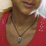 
              A necklace, half of a broken heart engraved with the word "Love," is worn by Anastasiia Aleksandrova, 12, at her home in Sloviansk, Donetsk region, eastern Ukraine, Monday, Aug. 8, 2022. Her best friend, Yeva, used to live on her street, but has evacuated with her family to western Ukraine. She misses her but they still share a special connection. Yeva, she said, wears the other half of the silver pendant. "I never take it off, and Yeva doesn't either," she said. (AP Photo/David Goldman)
            