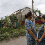 
              Valentyna Kondratieva, 75, left, is comforted by a neighbor as they stand outside her damaged home Saturday, Aug. 13, 2022, where she sustained injuries in a Russian rocket attack last night in Kramatorsk, Donetsk region, eastern Ukraine. The strike killed three people and wounded 13 others, according to the mayor. The attack came less than a day after 11 other rockets were fired at the city. (AP Photo/David Goldman)
            