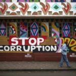 
              A man walks past a mural denouncing corruption in Nairobi, Kenya, Friday, Aug. 12, 2022. Vote-tallying in Kenya's close presidential election isn't moving fast enough, the electoral commission chair said Friday, while parallel counting by local media dramatically slowed amid concerns about censorship or meddling. (AP Photo/Mosa'ab Elshamy)
            
