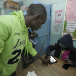 
              An election officer take the fingerprints in a general election at the Kangoni Primary School, Nairobi, Kenya, Tuesday, Aug. 9, 2022, with leading candidates Raila Odinga and William Auto vying to become the new president of East Africa's economic hub. (AP Photo/Sayyid Abdul Azim)
            