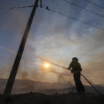 A firefighter sprays water on a power pole during a wildfire in Castaic, Calif. on Wednesday, Aug. 31, 2022. (AP Photo/Ringo H.W. Chiu)