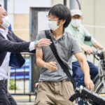 
              FILE - Tetsuya Yamagami, center, holding a weapon, is detained near the site of gunshots in Nara, western Japan Friday, July 8, 2022. Yamagami allegedly killed former Japanese Prime Minister Shinzo Abe during a campaign speech in Nara. A glimpse of his painful childhood has led to a surprising amount of sympathy in Japan, where three decades of economic malaise and social disparity have left many feeling isolated and unease. (Nara Shimbun/Kyodo News via AP, File)
            