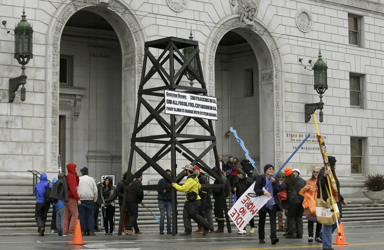 FILE - Protesters prepare to take down a makeshift oil derrick that was set up in front of the Cali...