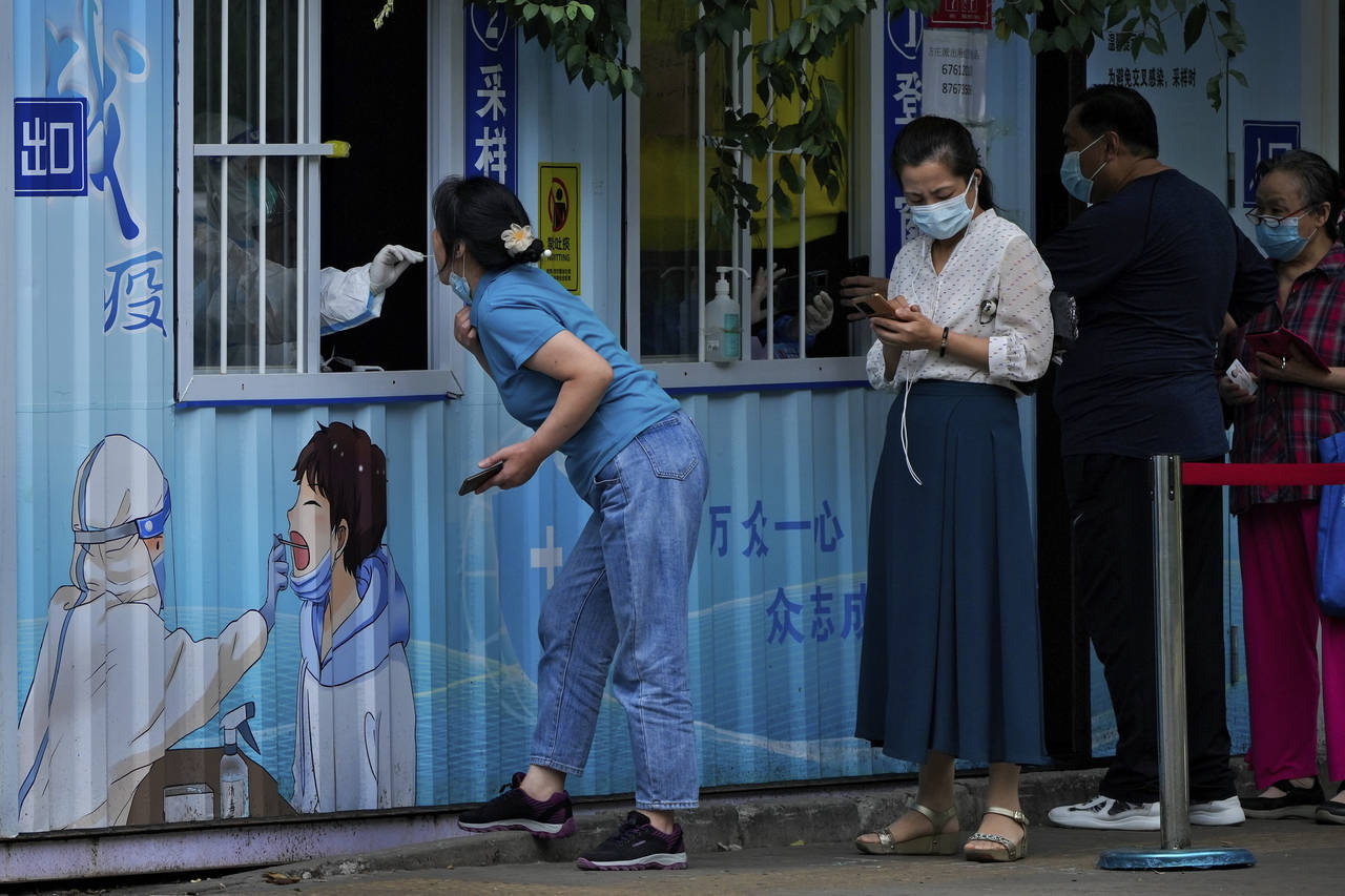 Residents get their routine COVID-19 throat swabs at a coronavirus testing site along a street in B...