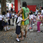 
              A girl holds on to his father during the opening of classes at the San Juan Elementary School in metro Manila, Philippines on Monday, Aug. 22, 2022. Millions of students wearing face masks streamed back to grade and high schools across the Philippines Monday in their first in-person classes after two years of coronavirus lockdowns that are feared to have worsened one of the world's most alarming illiteracy rates among children. (AP Photo/Aaron Favila)
            